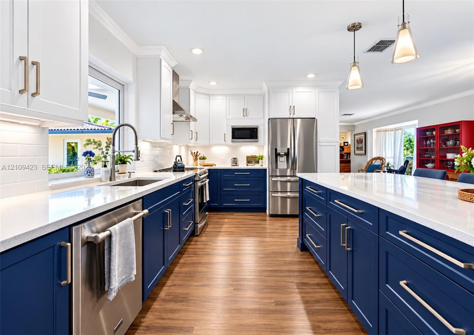 Kitchen featuring two-tone cabinetry, stone-finish countertops, stainless steel appliances, a center island, and wood-finish flooring