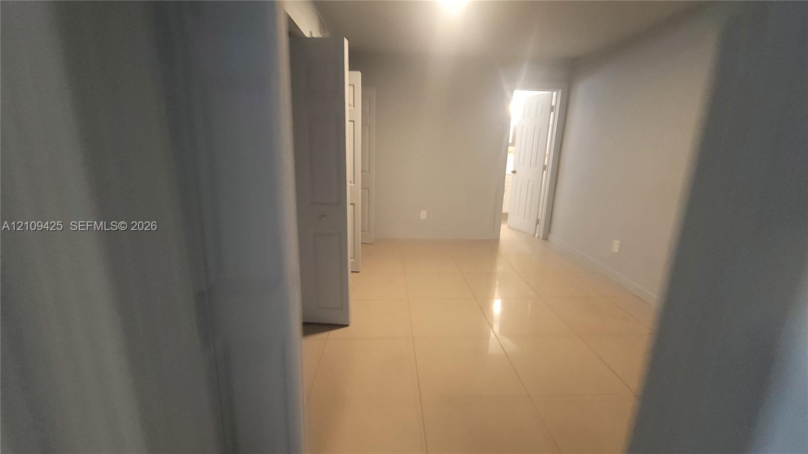 Neutral-toned room featuring large-format tile flooring and bi-fold closet doors