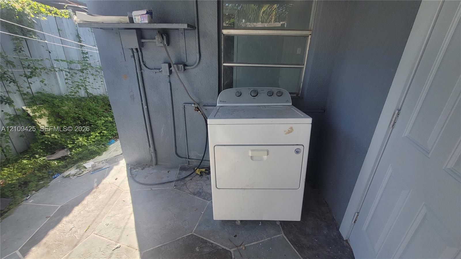 Exterior area featuring a concrete-tiled floor, masonry walls, and a dedicated laundry appliance hookup