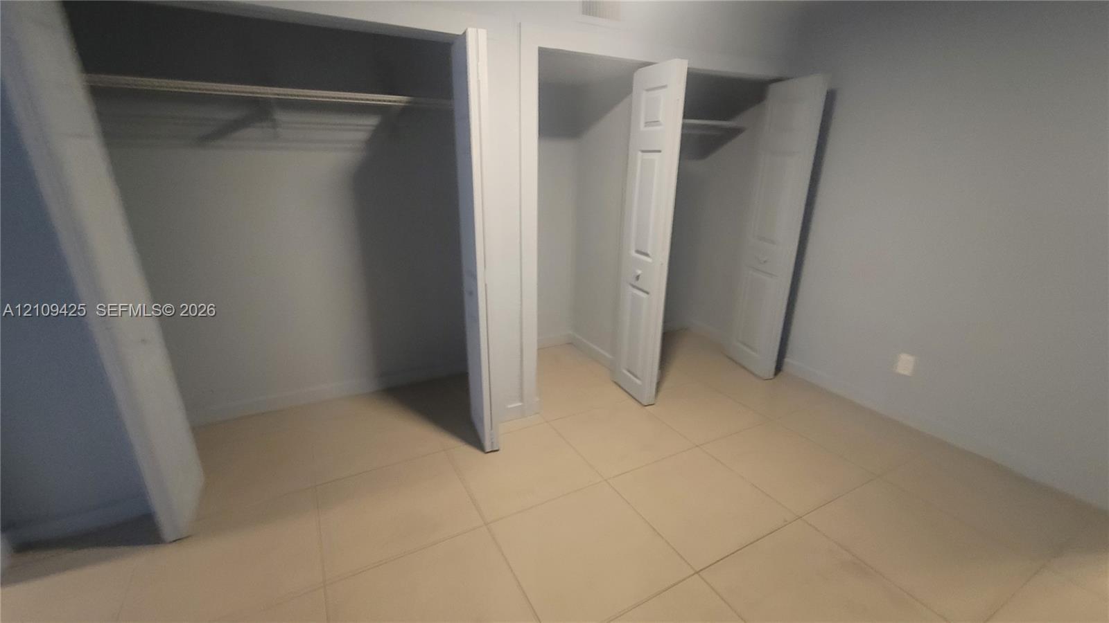 Interior space featuring ceramic tile flooring, two separate closets with paneled doors, and built-in shelving