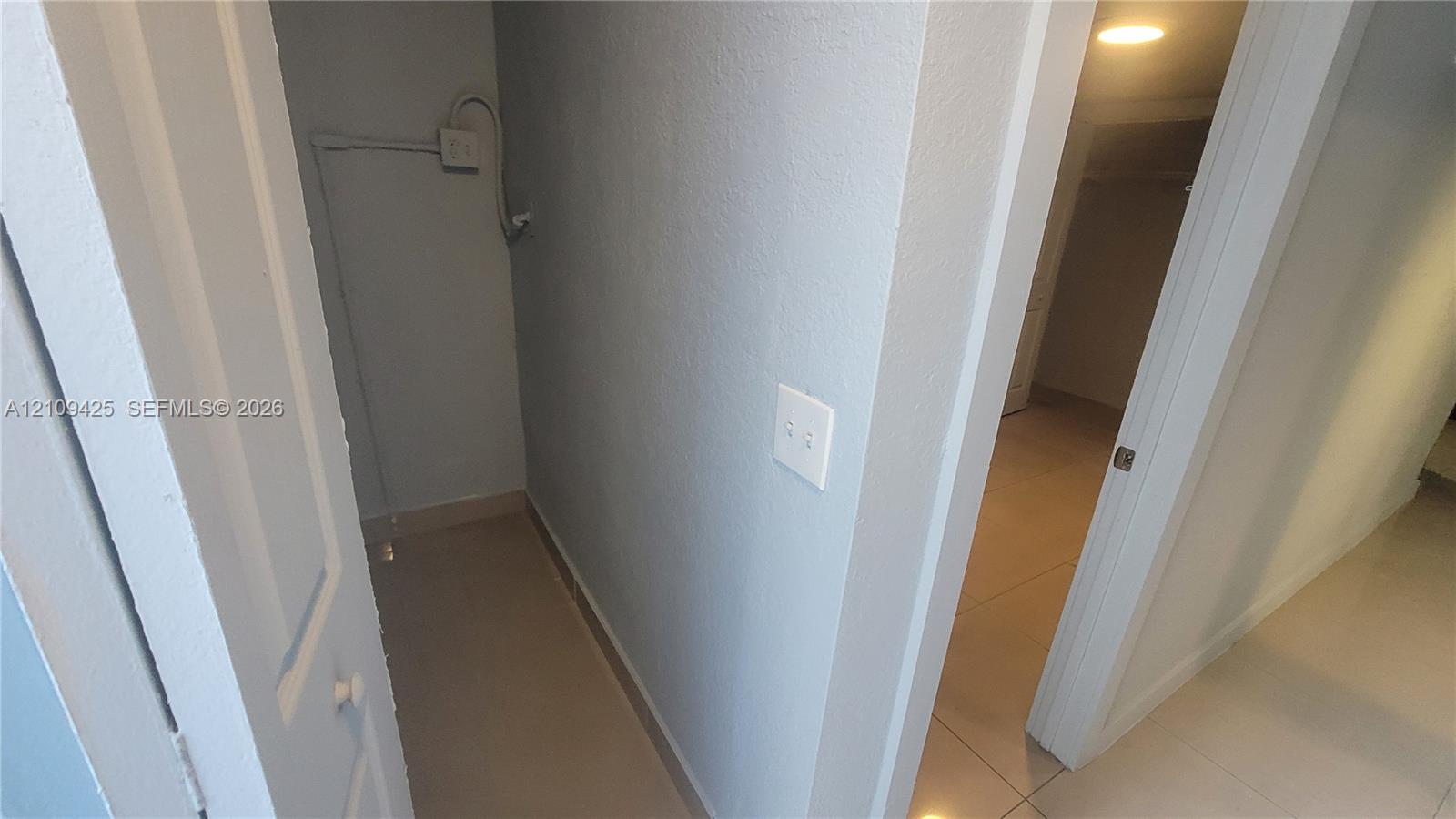 Storage alcove featuring neutral wall finishes and oversized floor tile