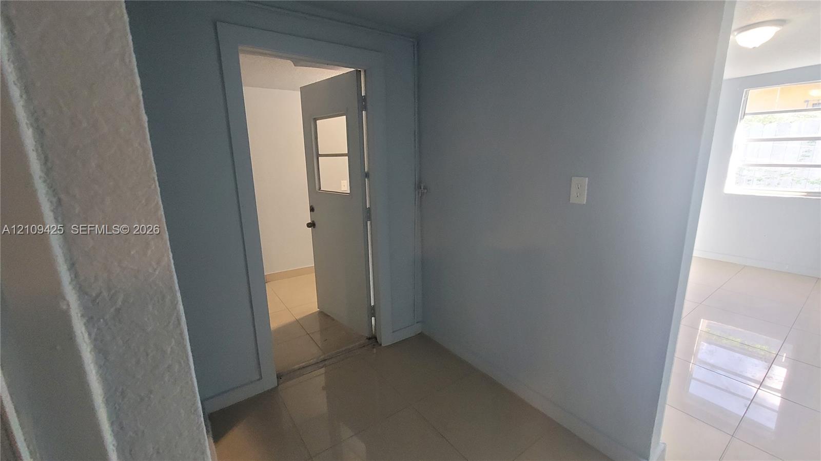 Large-format tile flooring, single-light door with inset window, and recessed ceiling lighting