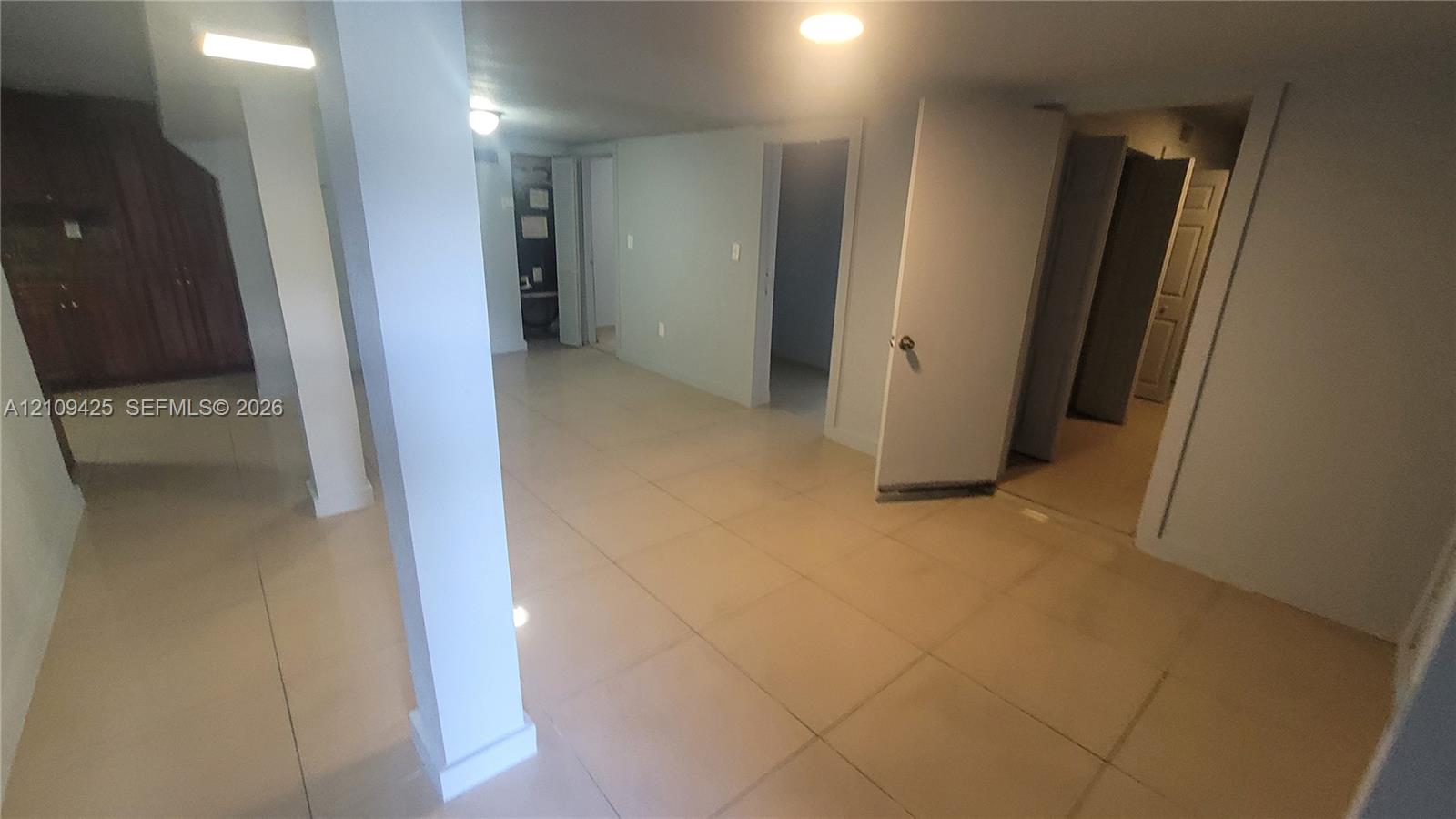 Large-format tile flooring, structural support column, recessed lighting, and built-in wood cabinetry