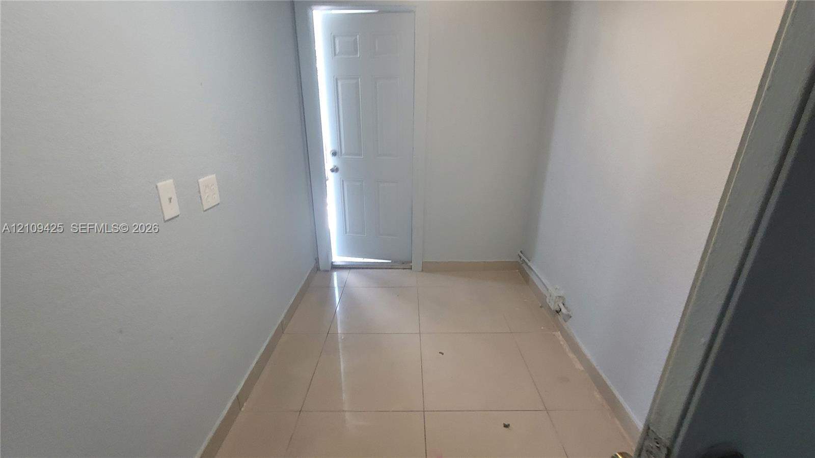 Interior space featuring neutral wall paint, large-format tile flooring, and a six-panel exterior door