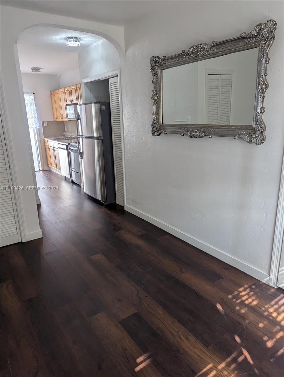 Interior featuring dark wood-finish flooring, an arched entryway, louvered closet doors, and recessed lighting