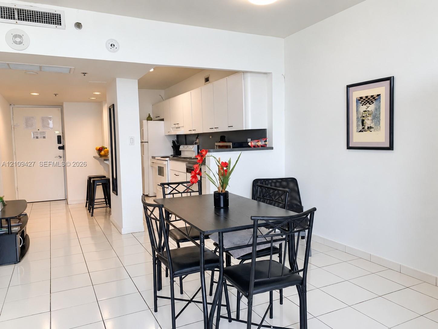 Kitchen featuring white cabinetry and built-in appliances, ceramic tile flooring, and a breakfast bar