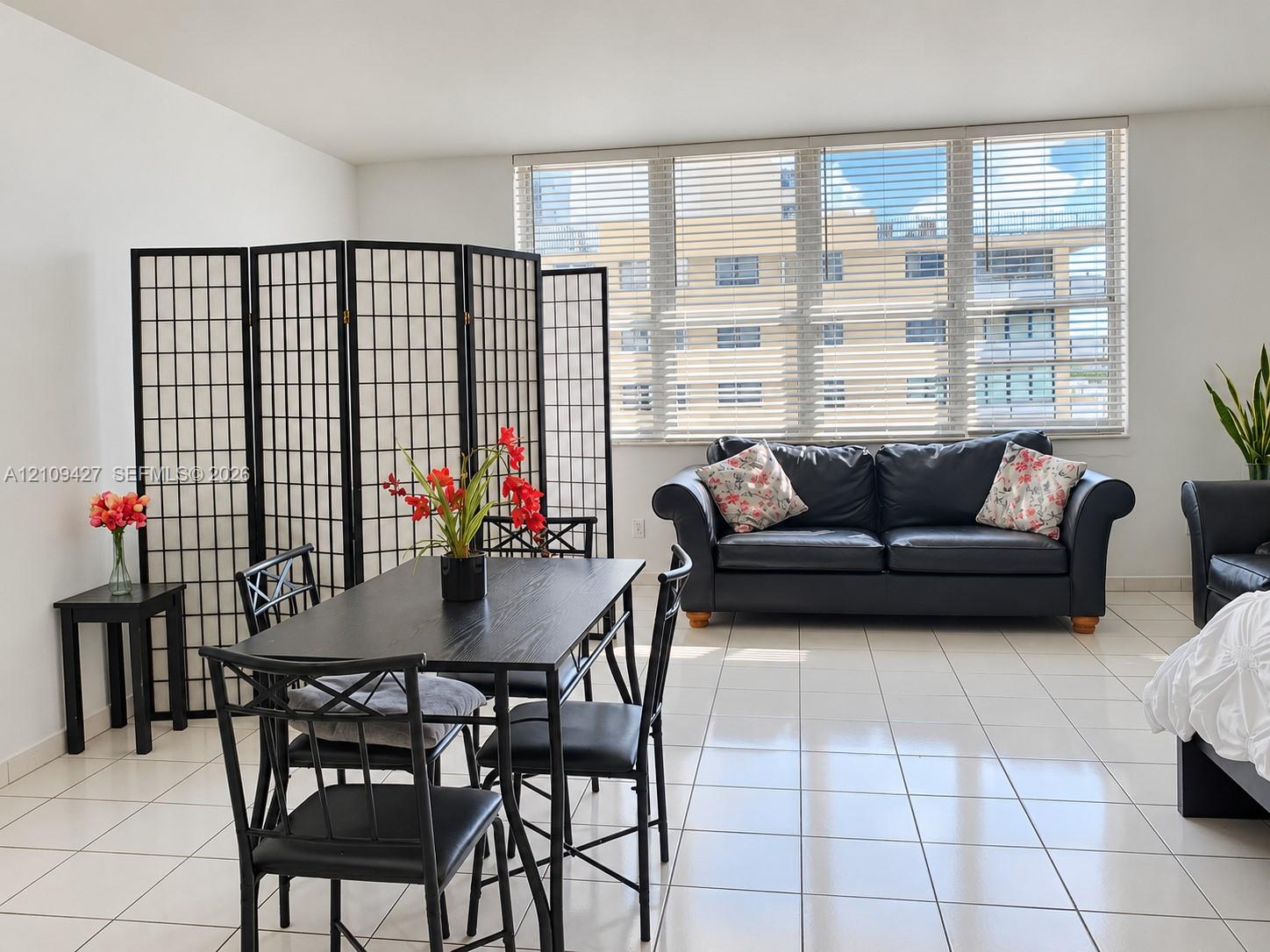Open-concept living space featuring ceramic tile flooring and expansive, multi-pane windows with horizontal blinds