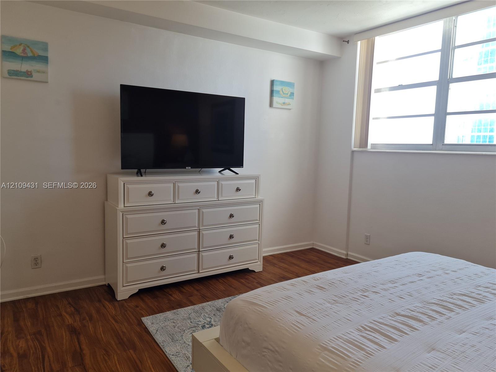 Wood-finish flooring throughout the room with a bold accent wall