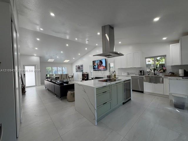 Kitchen featuring a central island with a stone-finish waterfall countertop, stainless steel chimney-style range hood, recessed lighting, tile flooring, and vaulted ceiling