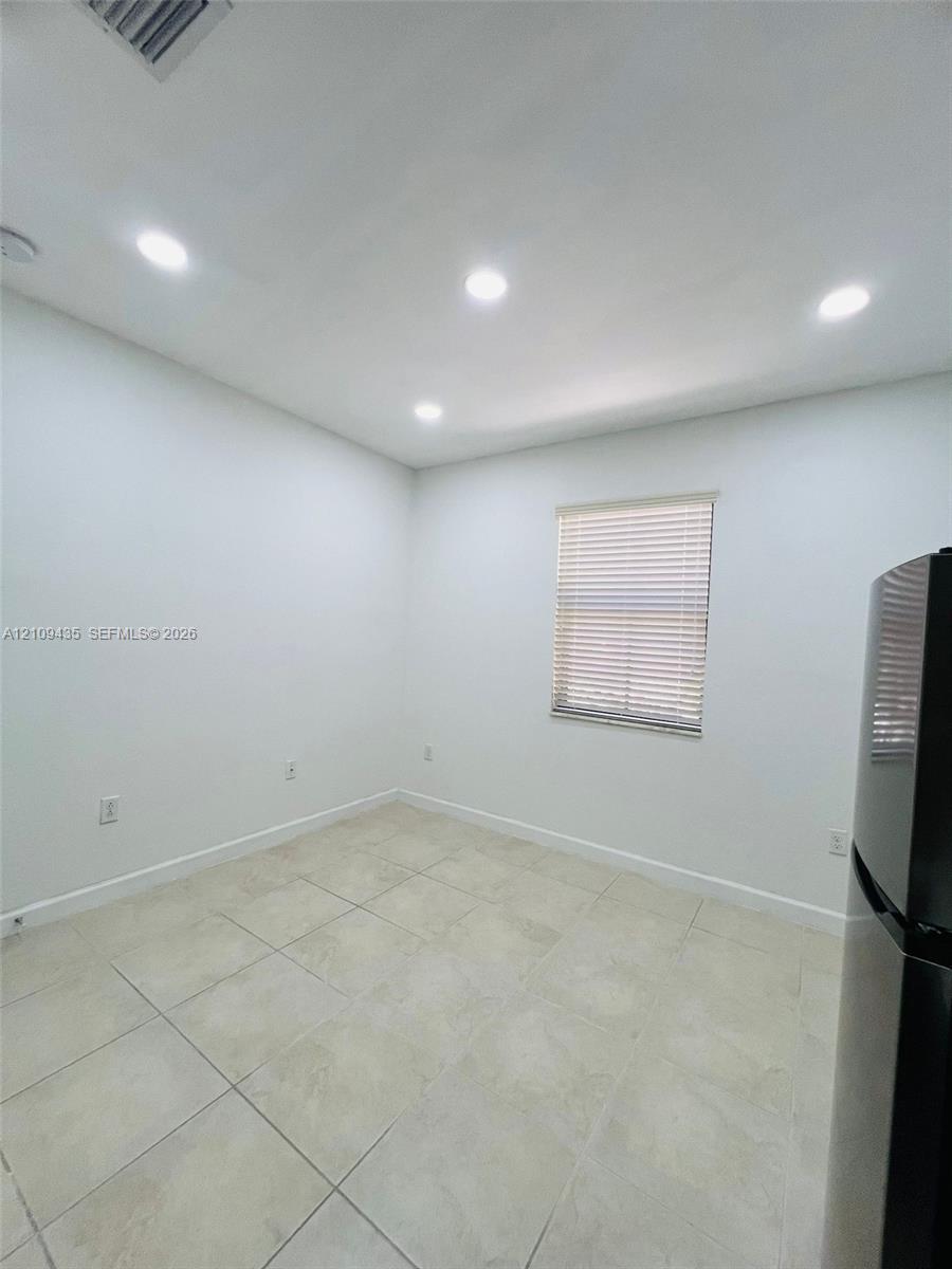 Neutral-toned tile flooring, recessed ceiling lighting, and a window with horizontal blinds