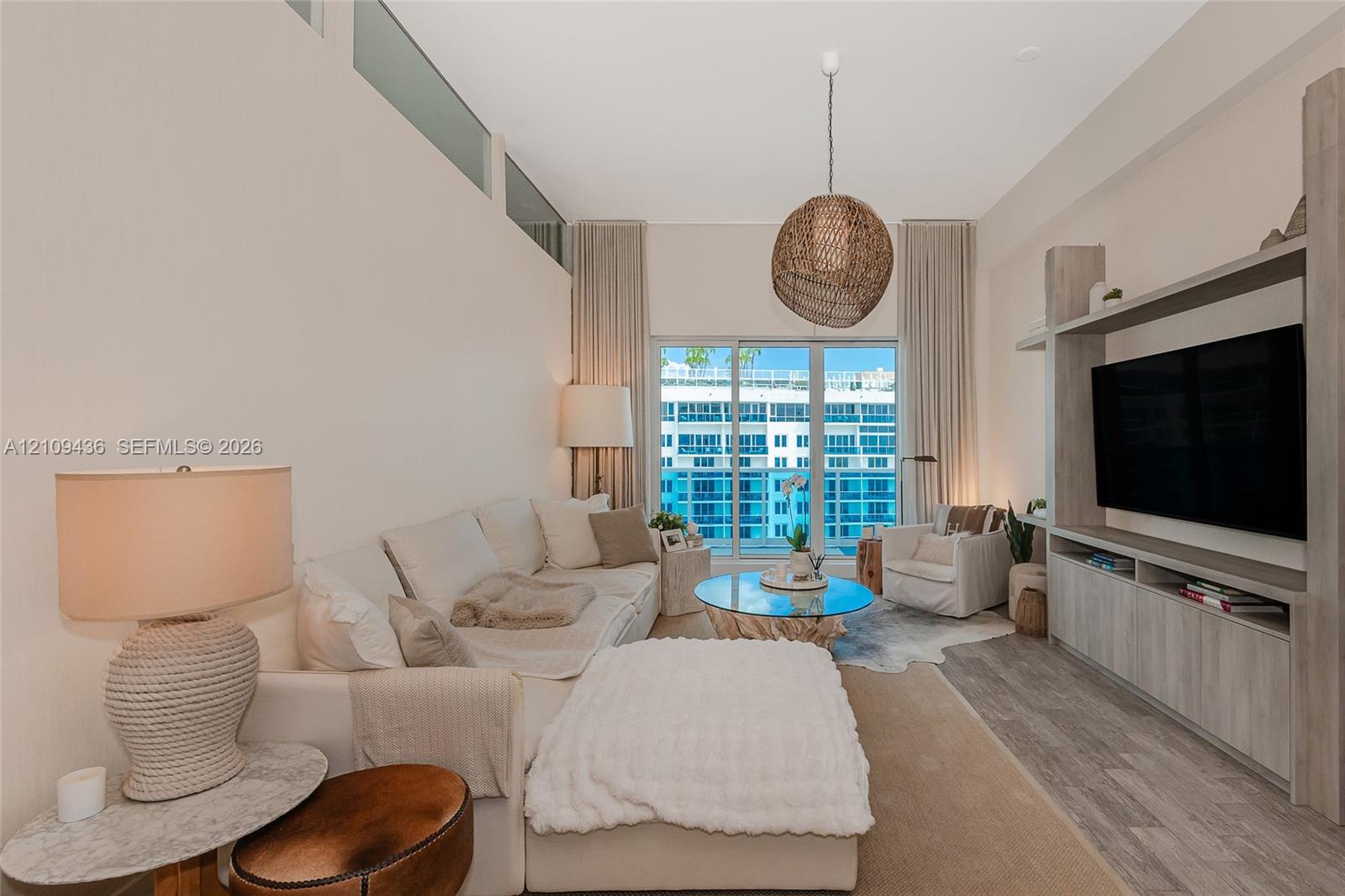 Living area featuring high ceilings with transom windows, full-height sliding glass doors, built-in media cabinetry, and wood-finish flooring