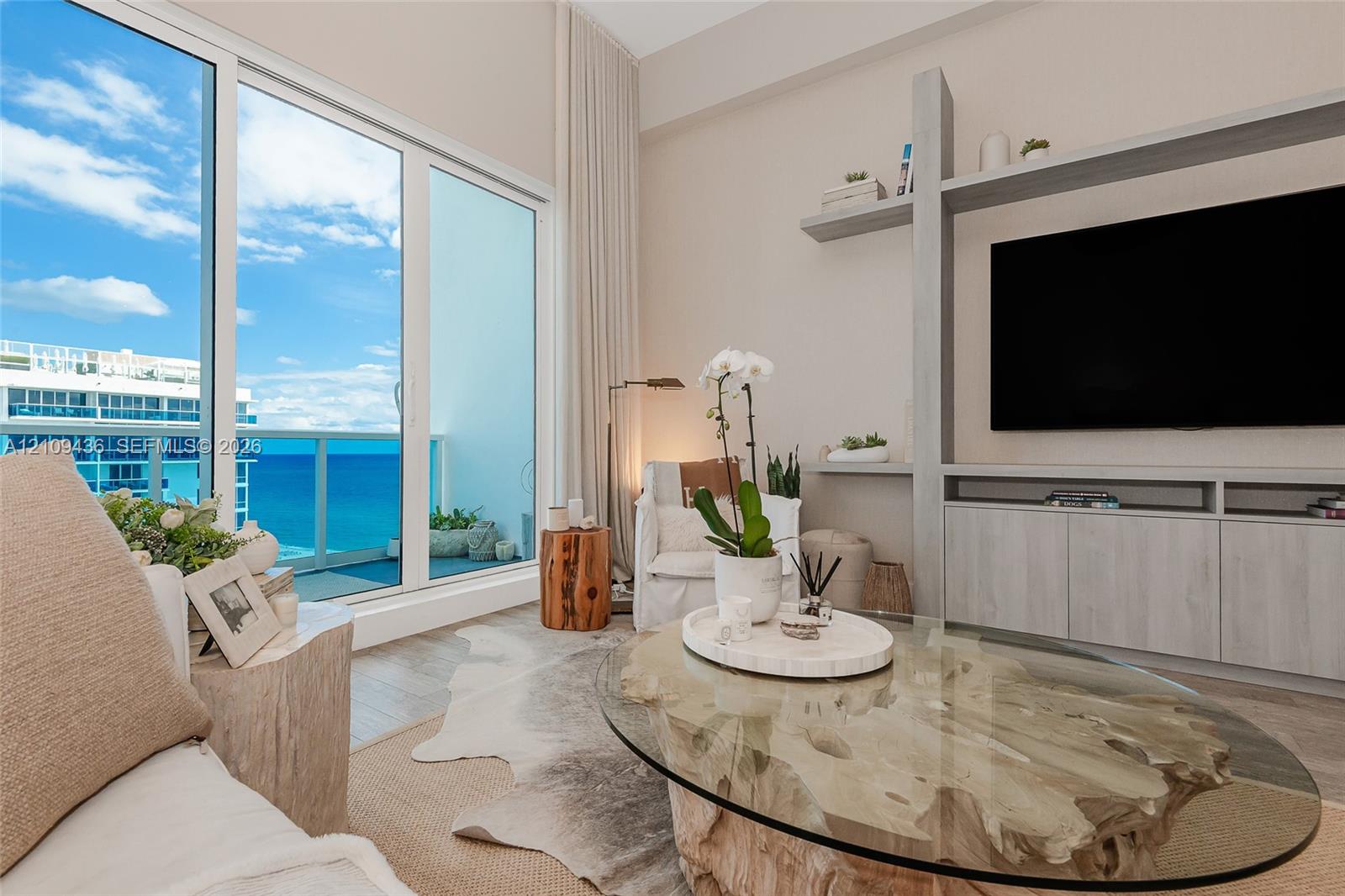 Floor-to-ceiling sliding glass doors, custom built-in media cabinetry with integrated shelving, and wood-finish flooring