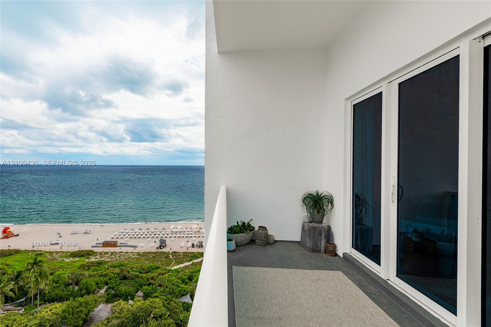Covered balcony featuring concrete flooring, a white structural railing, and sliding glass panel doors