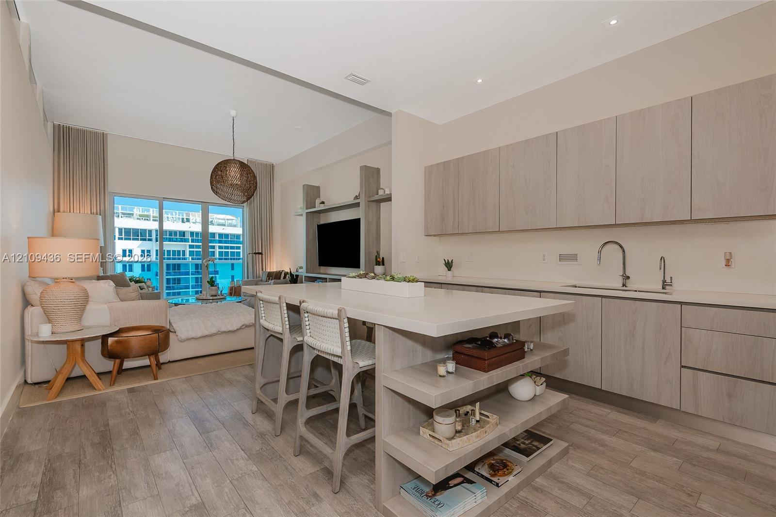 Open-concept kitchen featuring wood-finish cabinetry, a central island with integrated shelving, quartz countertops, wood-finish flooring, and recessed lighting