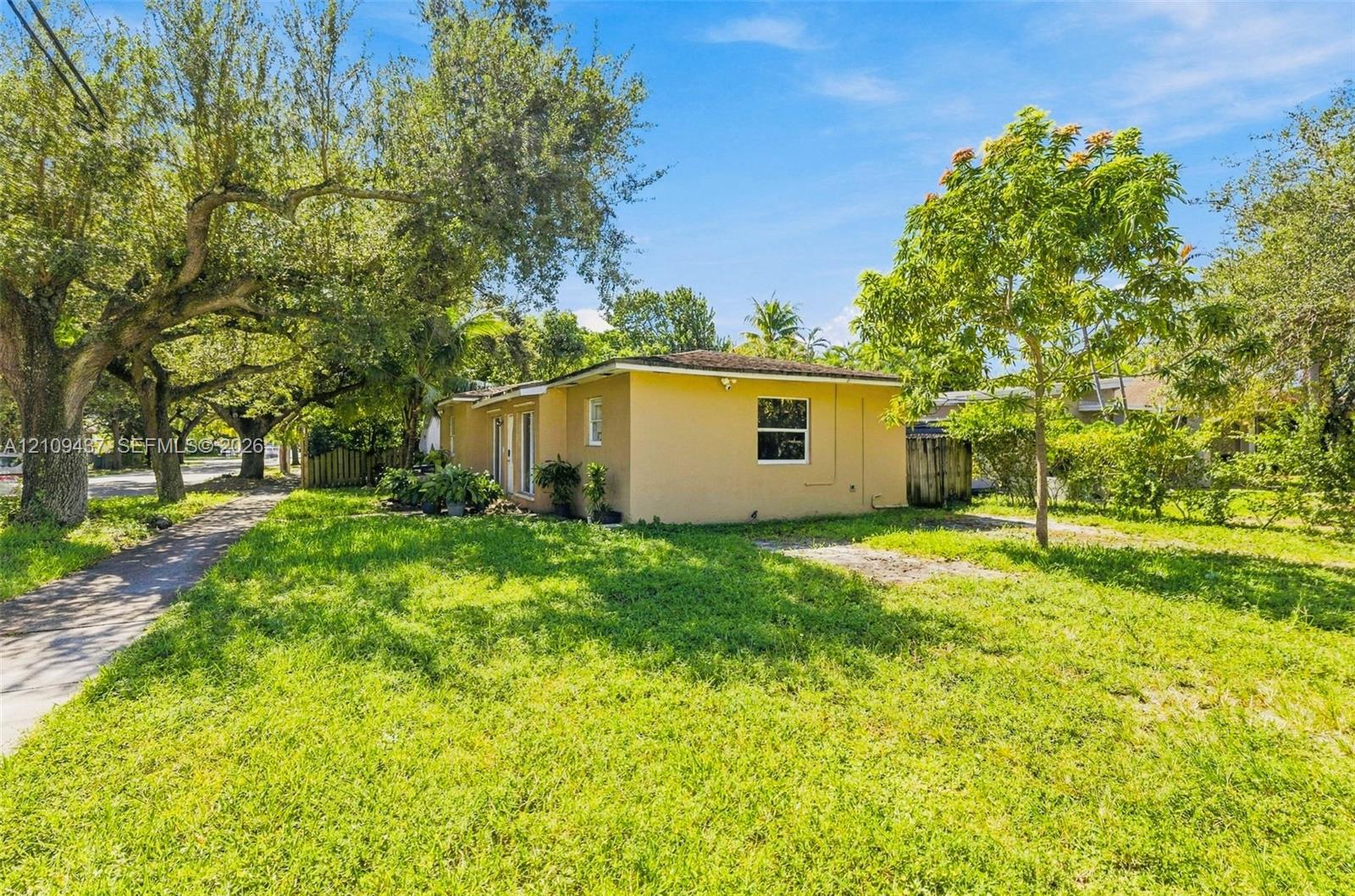 Single-story residence featuring a stucco exterior, single-hung windows, and expansive grounds shaded by mature trees Single-story residence featuring a stucco exterior, single-hung windows, and expansive grounds shaded by mature trees