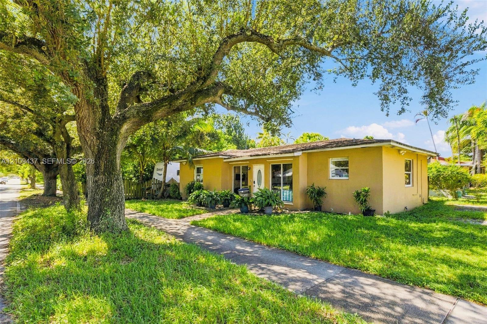 Stucco exterior residence featuring mature oak trees, a concrete walkway, and expansive green space Stucco exterior residence featuring mature oak trees, a concrete walkway, and expansive green space