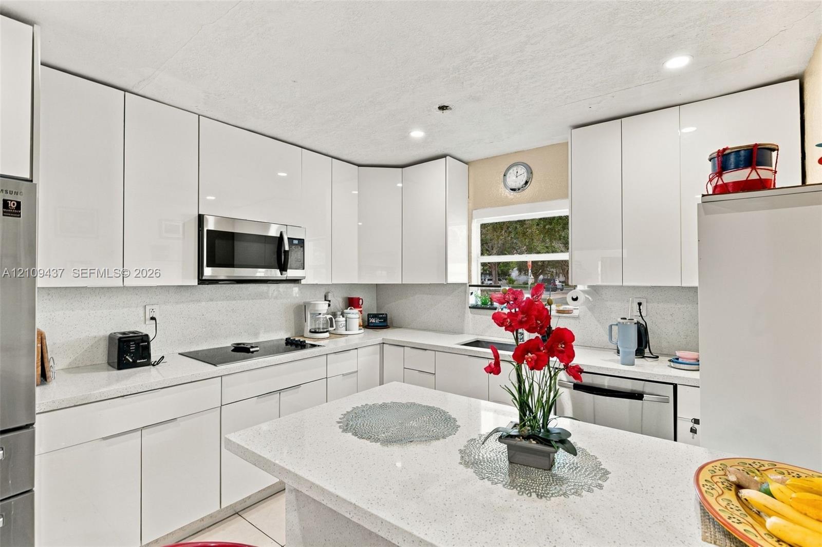 Kitchen featuring white gloss cabinetry, stone-finish countertops, stainless steel built-in appliances, recessed lighting, and an island Kitchen featuring white gloss cabinetry, stone-finish countertops, stainless steel built-in appliances, recessed lighting, and an island