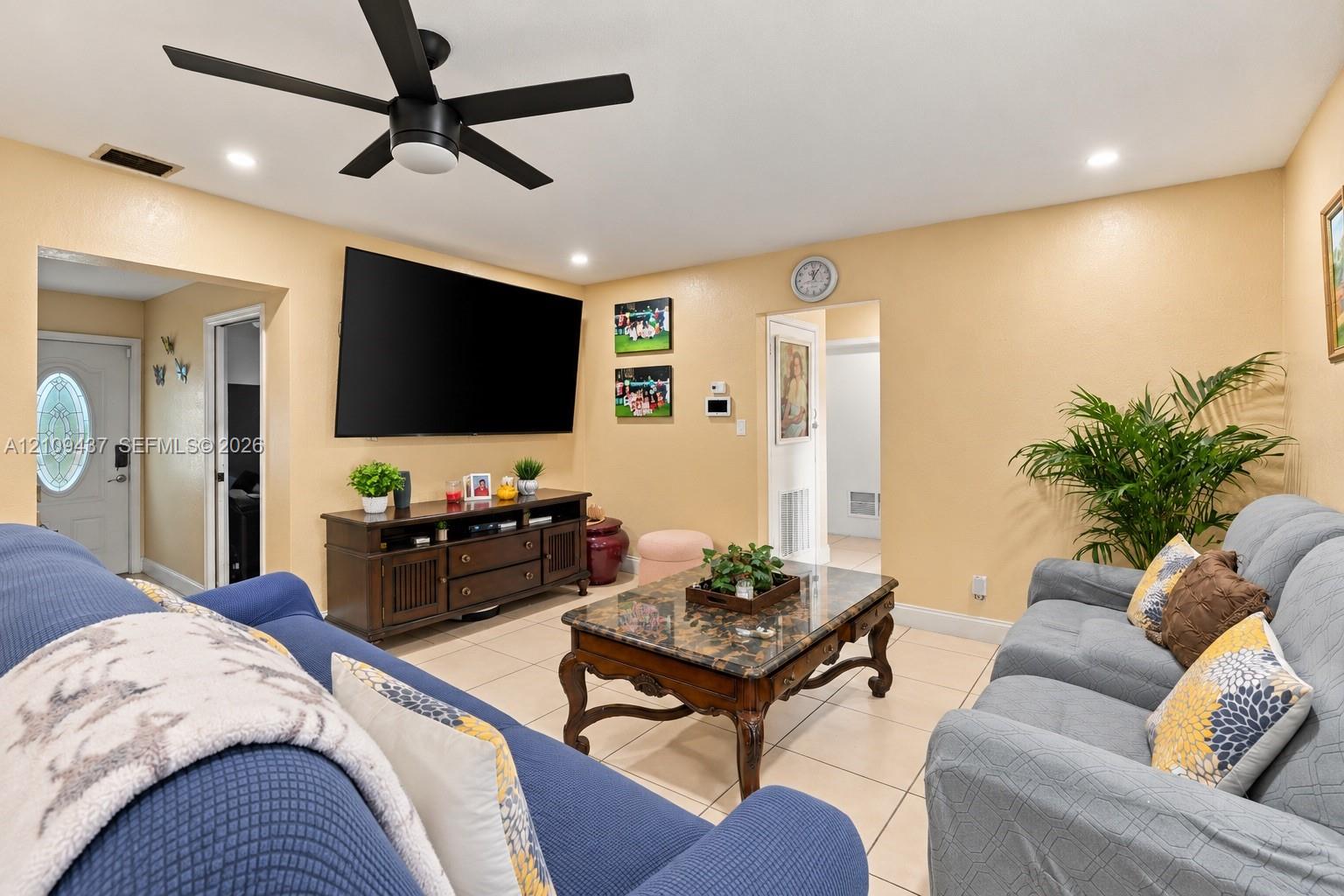 Living area featuring large-format tile flooring, matte black ceiling fan, and recessed lighting Living area featuring large-format tile flooring, matte black ceiling fan, and recessed lighting