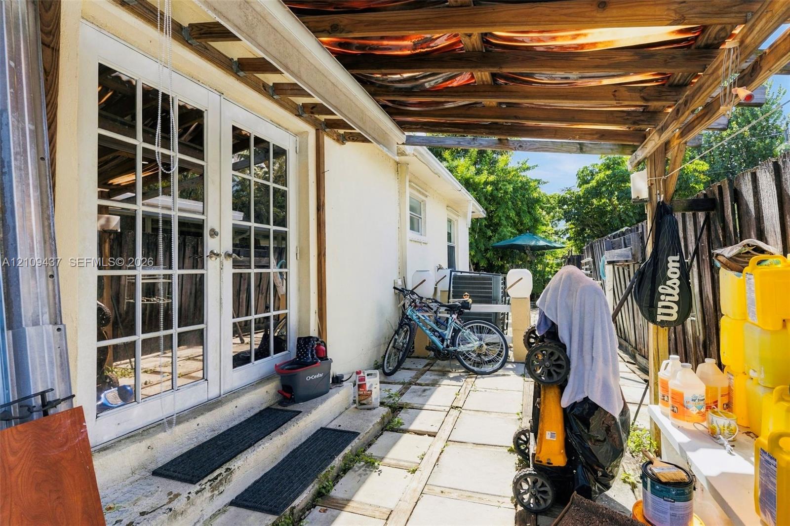 Exterior space featuring a wood-frame pergola, white-framed French doors, and paved patio surfacing