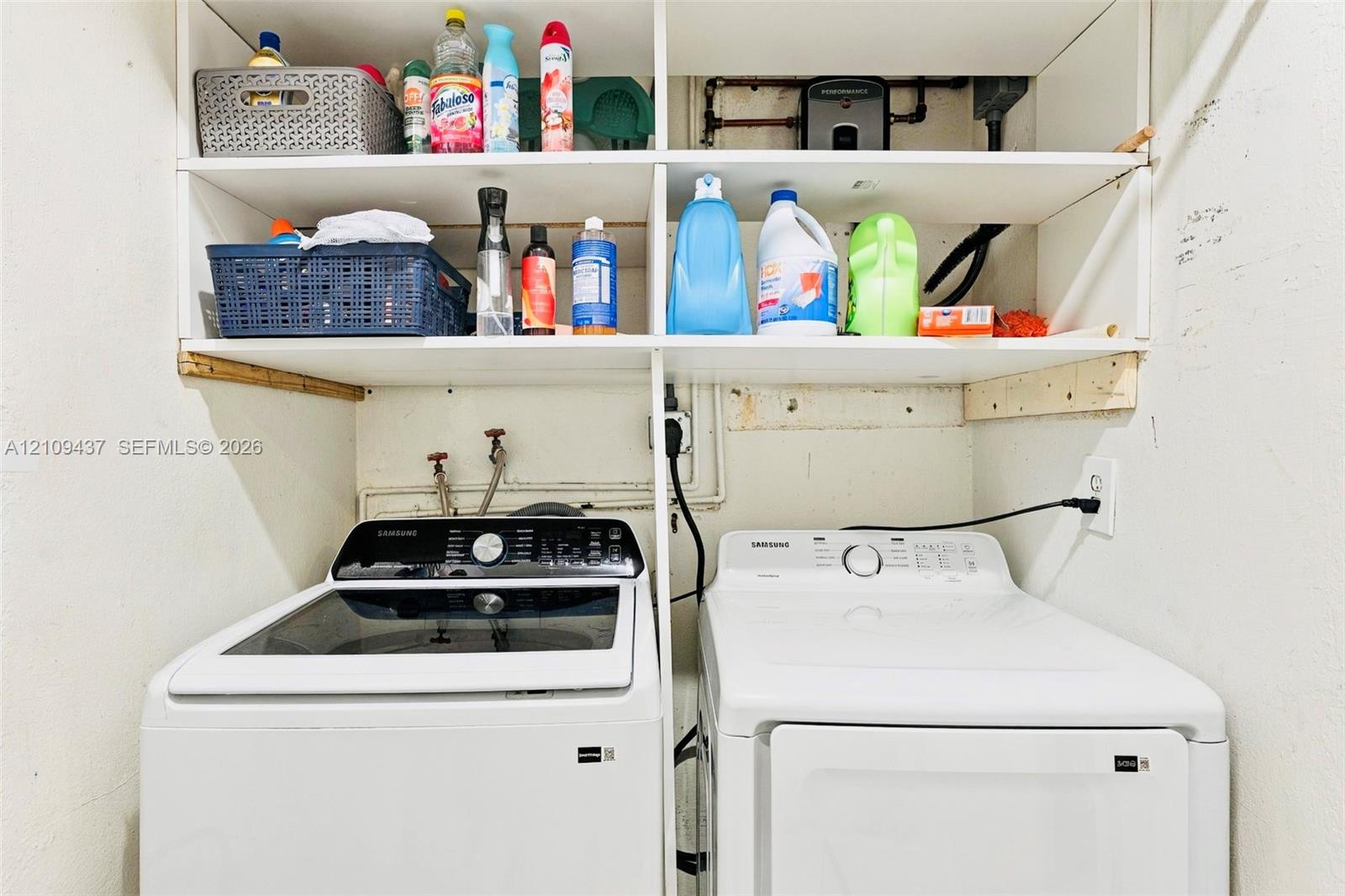 Laundry area featuring built-in white shelving and a side-by-side washer and dryer set