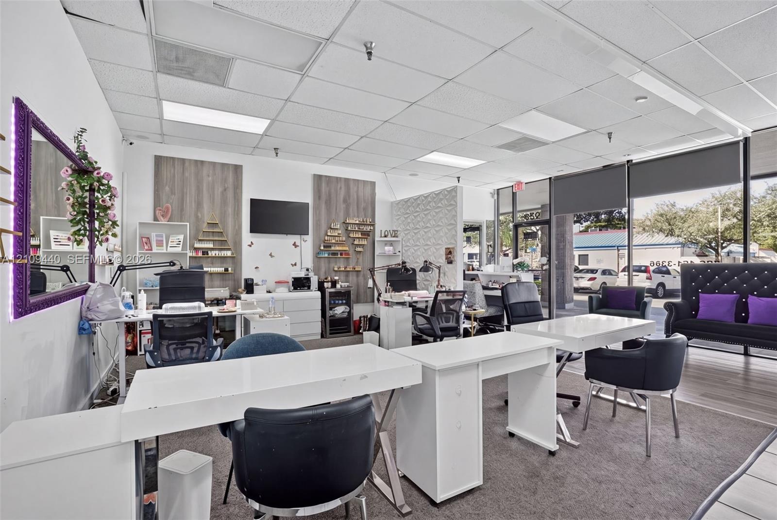 Commercial interior space featuring a drop ceiling with recessed lighting, full-height storefront glass windows, patterned accent wall detailing, wood-finish wall panels, and carpeted flooring