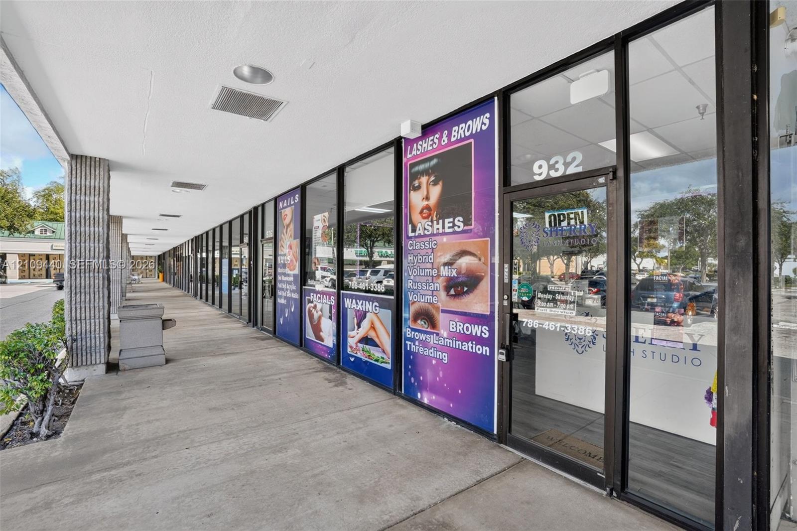 Commercial storefront featuring a full-height glass facade with aluminum framing, concrete walkway, and recessed ceiling lighting