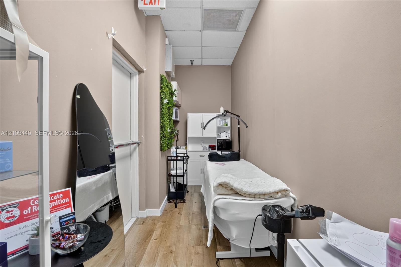 Enclosed interior space featuring wood-finish flooring, white built-in cabinetry, and a drop ceiling
