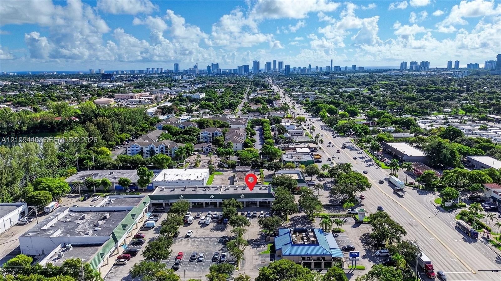 Commercial property featuring prominent street frontage, multi-tenant storefront configuration, asphalt surface parking, and roof-mounted mechanical units