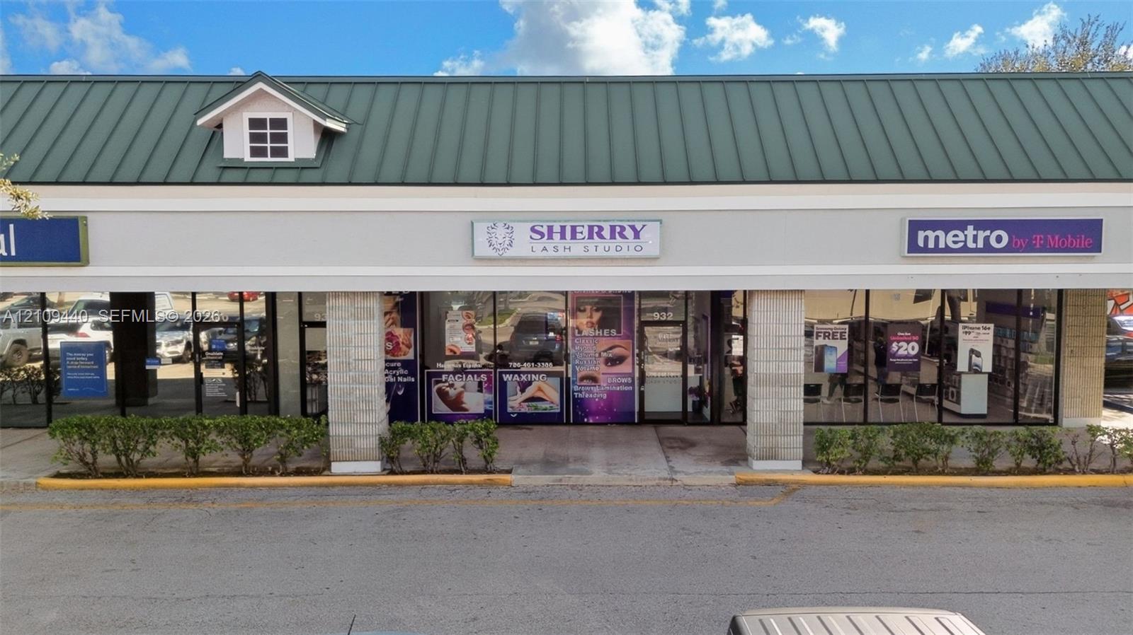 Commercial storefront featuring a green metal gable roof, expansive glass frontage, and stone-faced support columns