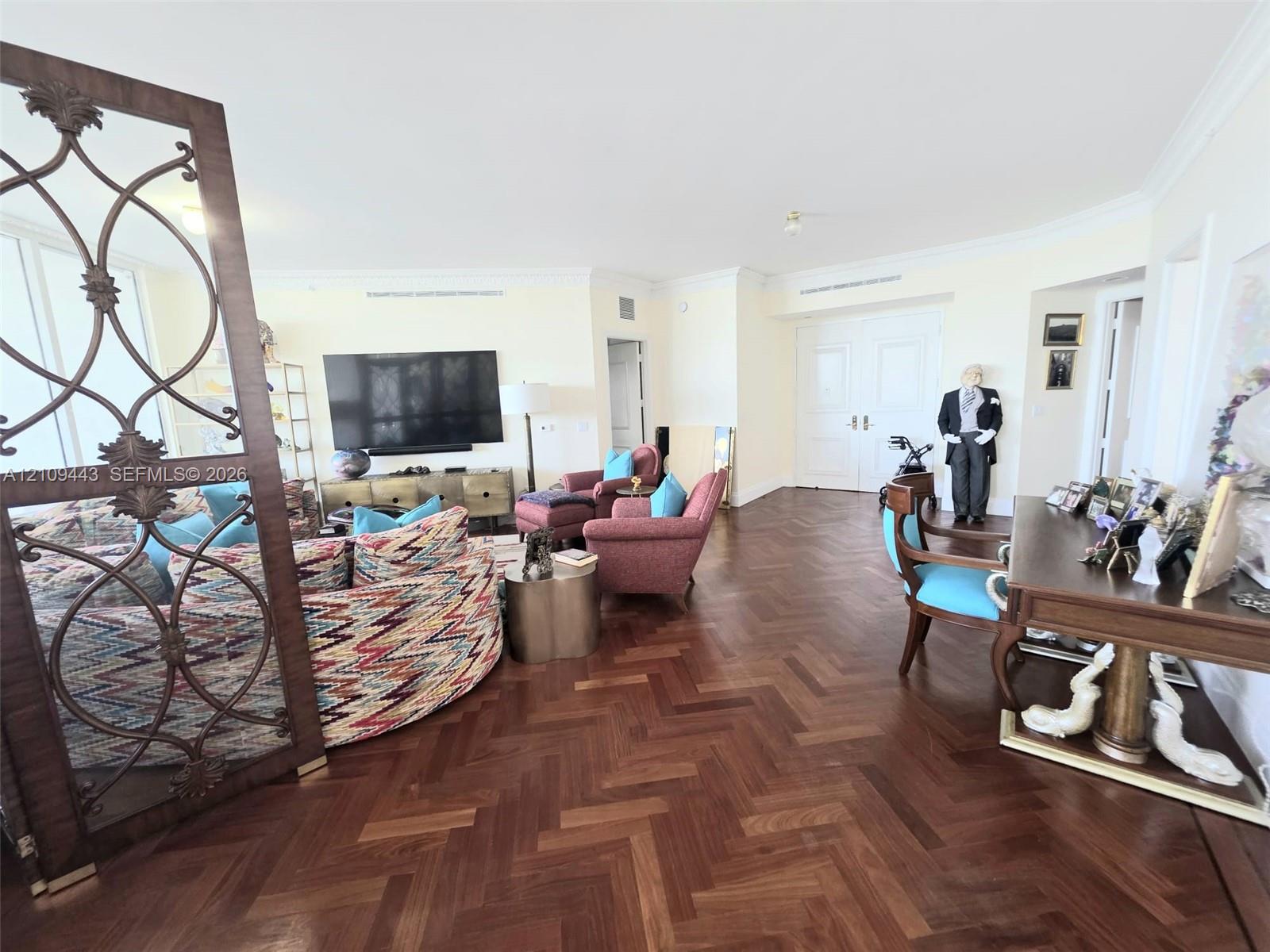 Herringbone-patterned wood-finish flooring, decorative metal room divider, and double-door entry