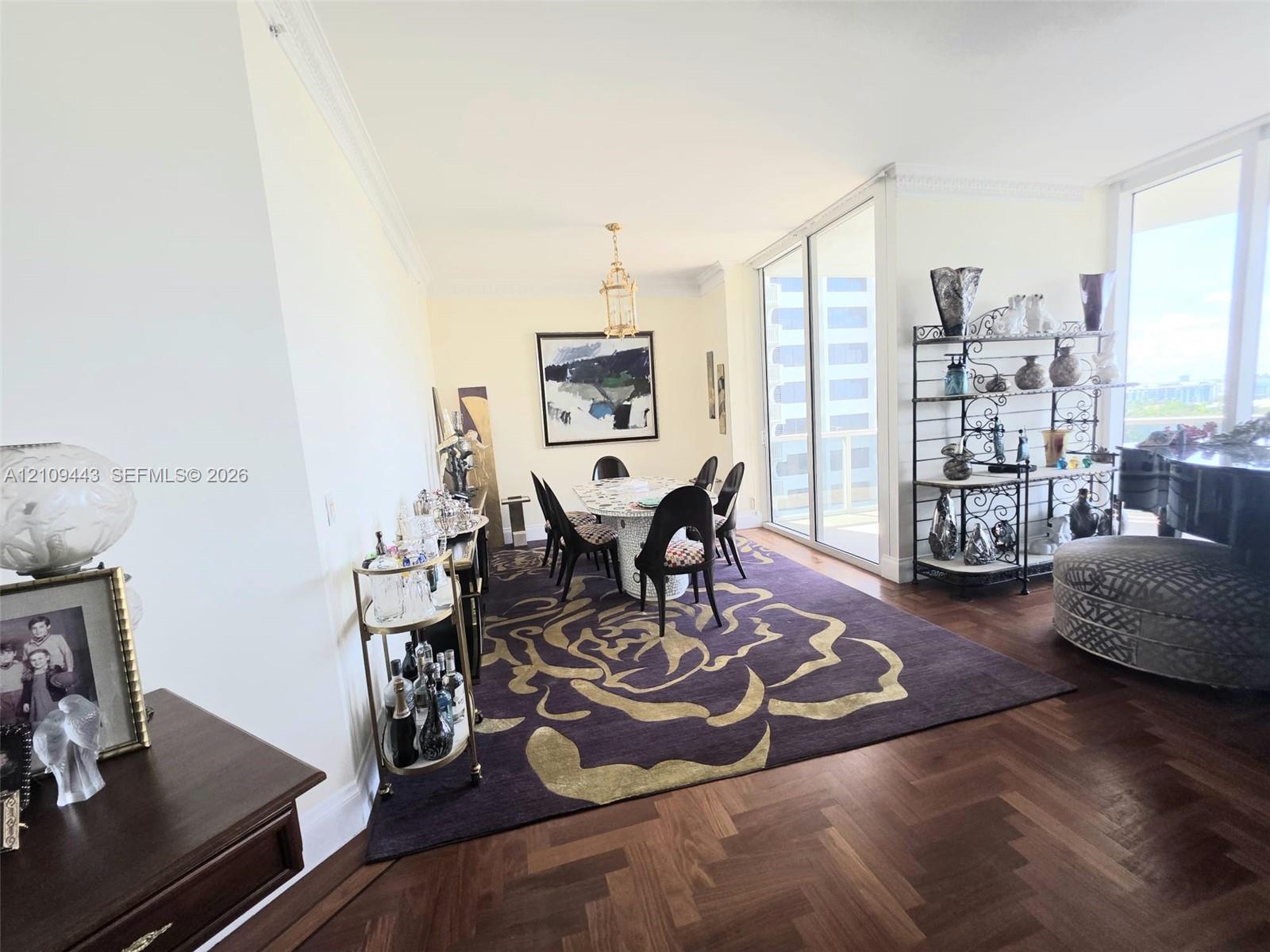 Herringbone-patterned wood-finish flooring, crown molding, and floor-to-ceiling glass sliding doors opening to an exterior space