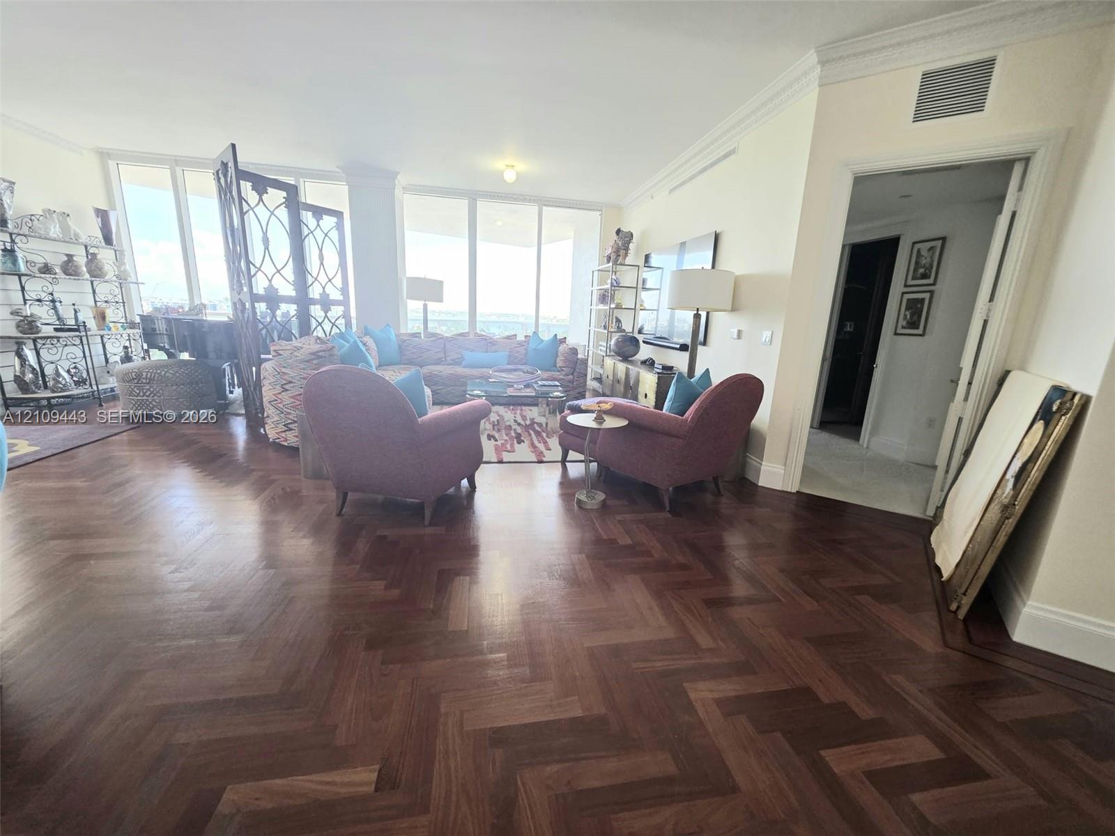 Herringbone-patterned wood-finish flooring, floor-to-ceiling windows, and crown molding