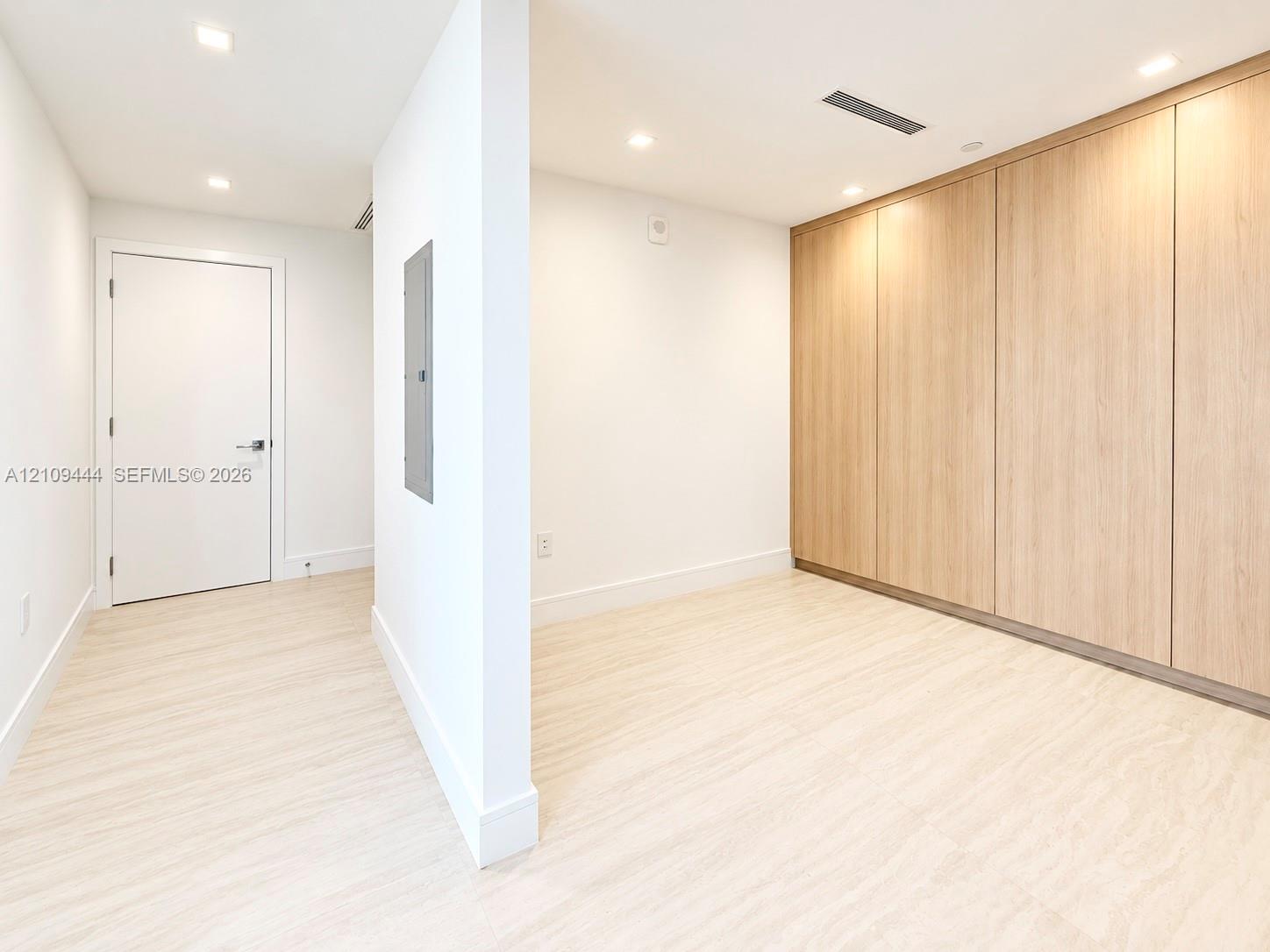 Floor-to-ceiling wood-finish cabinetry, recessed lighting, and wood-finish flooring