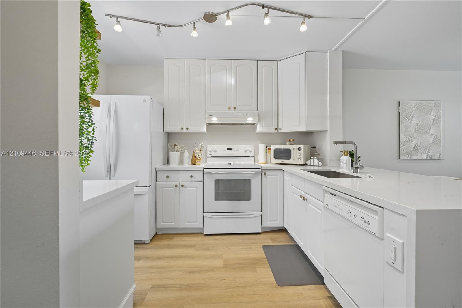 Kitchen featuring white cabinetry, solid-surface countertops, wood-finish flooring, and adjustable track lighting