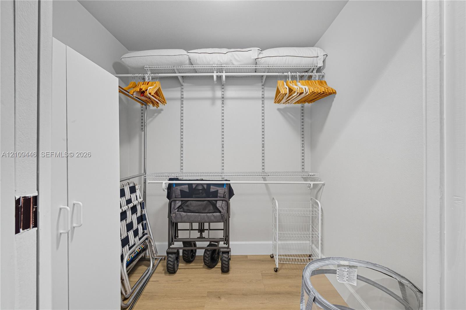 Walk-in closet featuring white walls, wood-finish flooring, and white wire shelving with integrated hanging rods