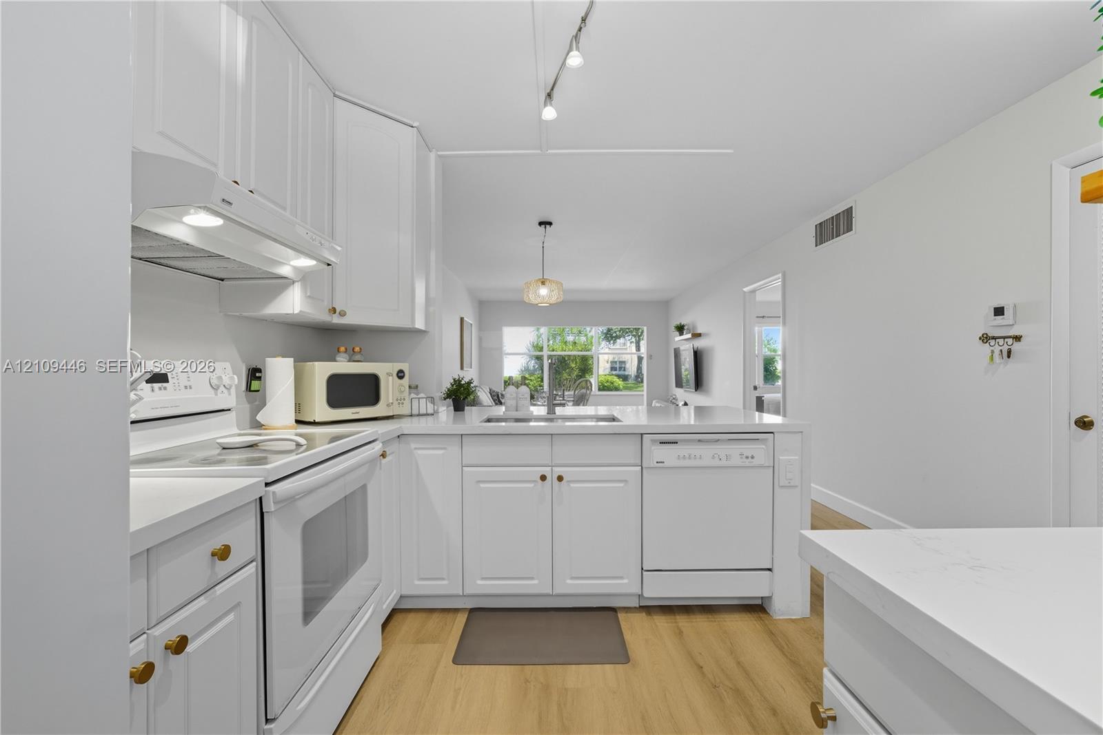 Kitchen featuring white shaker-style cabinetry, wood-finish flooring, white appliances, and track lighting