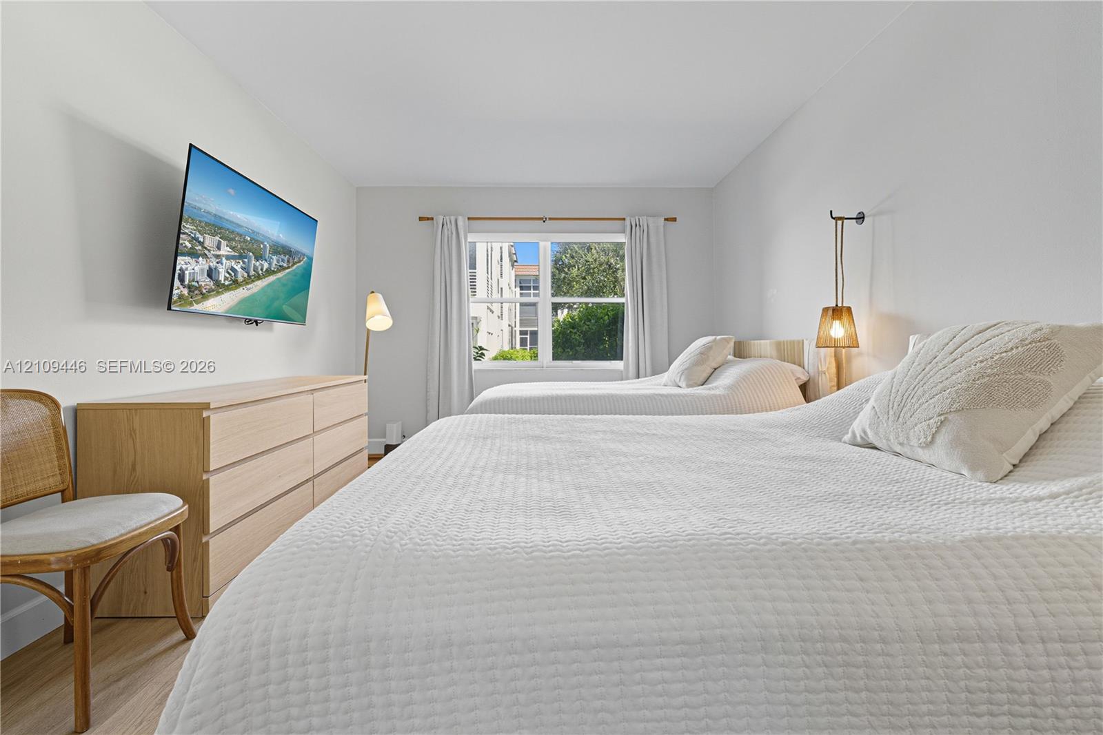 Neutral-toned bedroom featuring wood-finish flooring and a central window with white trim