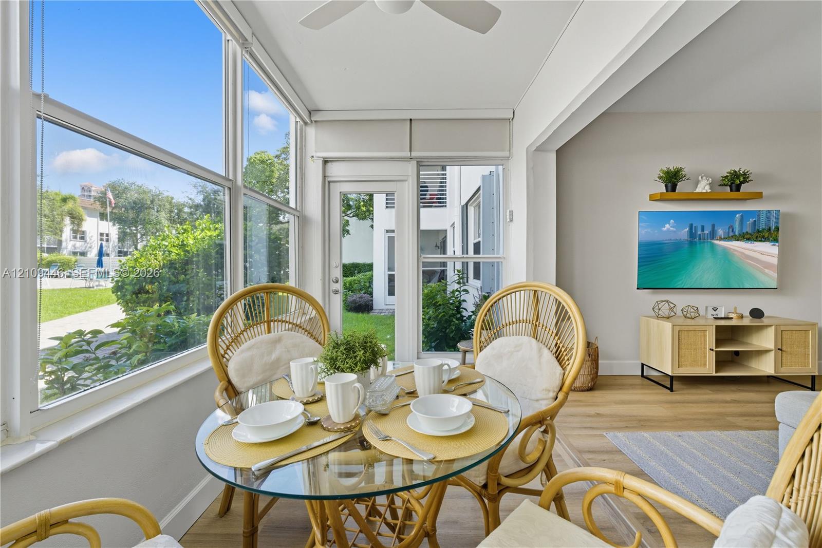Sunroom featuring expansive multi-pane windows, wood-finish flooring, a ceiling-mounted fan, and a glass-paneled exterior door Sunroom featuring expansive multi-pane windows, wood-finish flooring, a ceiling-mounted fan, and a glass-paneled exterior door