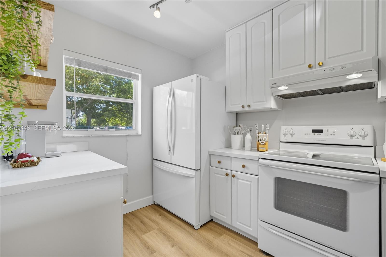 Kitchen featuring white cabinetry, wood-finish flooring, solid surface countertops, and white appliances including a range with an integrated hood
