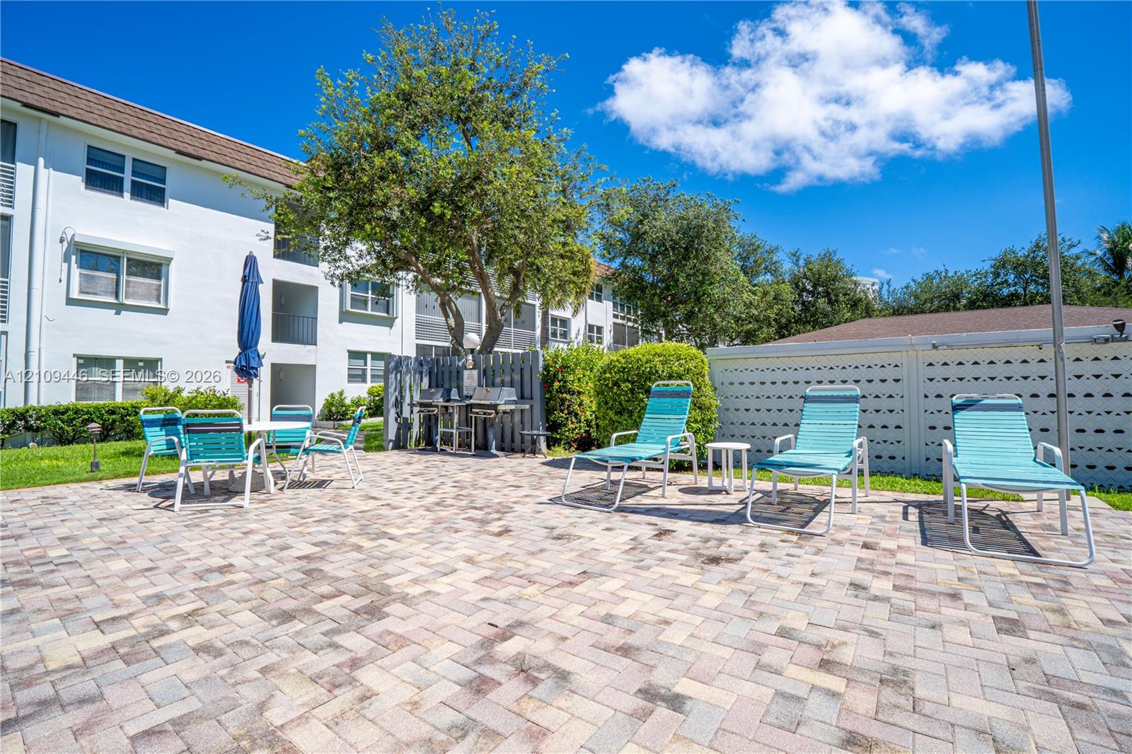 Outdoor patio featuring herringbone-patterned stone pavers, privacy screening, and built-in stainless steel grilling station