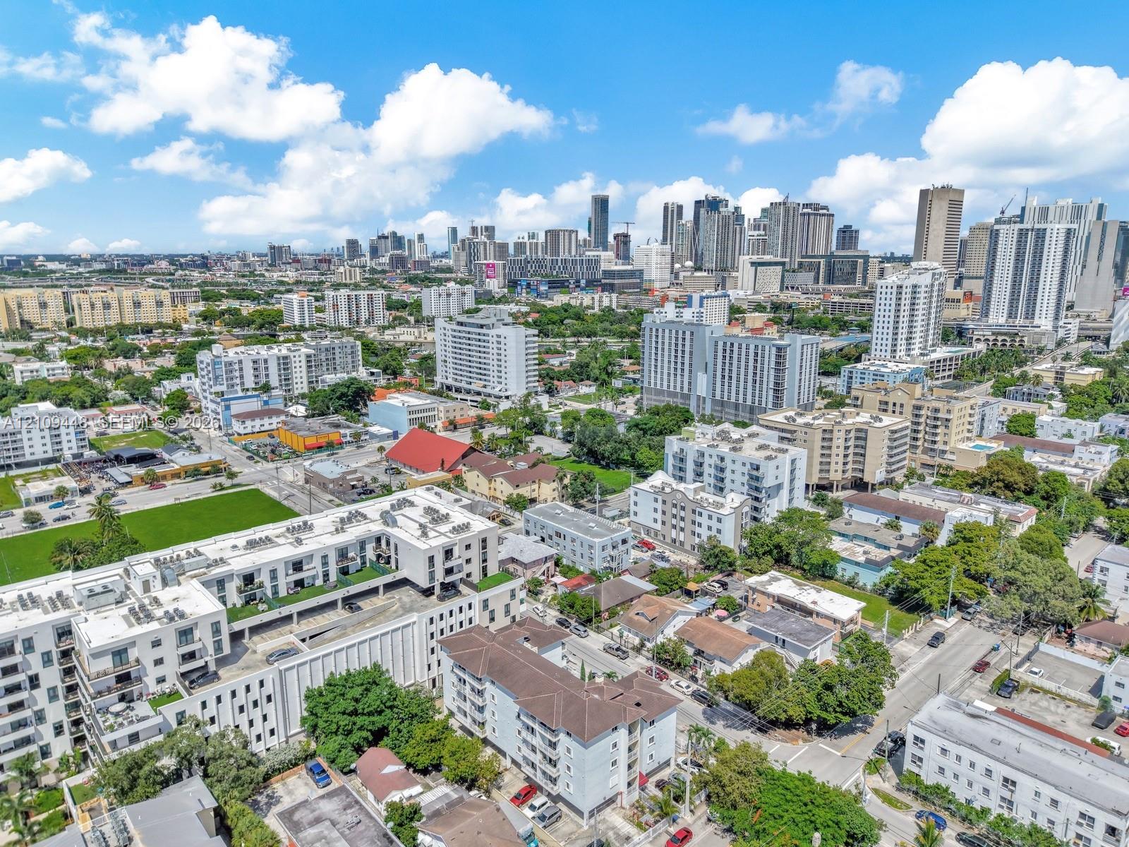 Aerial perspective of a multi-story residential building featuring a structured parking facility, flat roof architecture, and proximity to the urban skyline