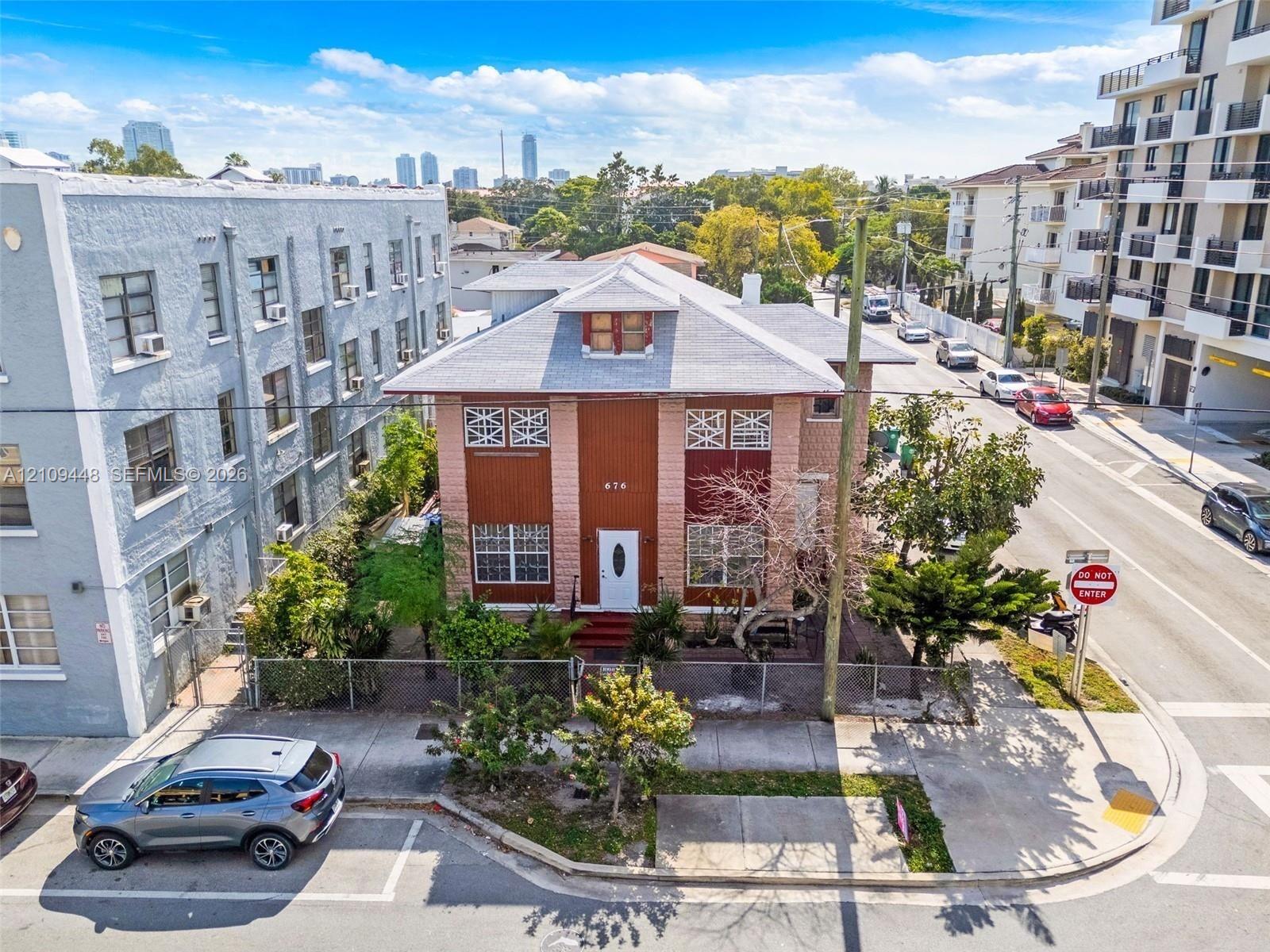 Two-story multi-family structure with a hipped roof, dormer window, masonry facade, and perimeter chain-link fencing