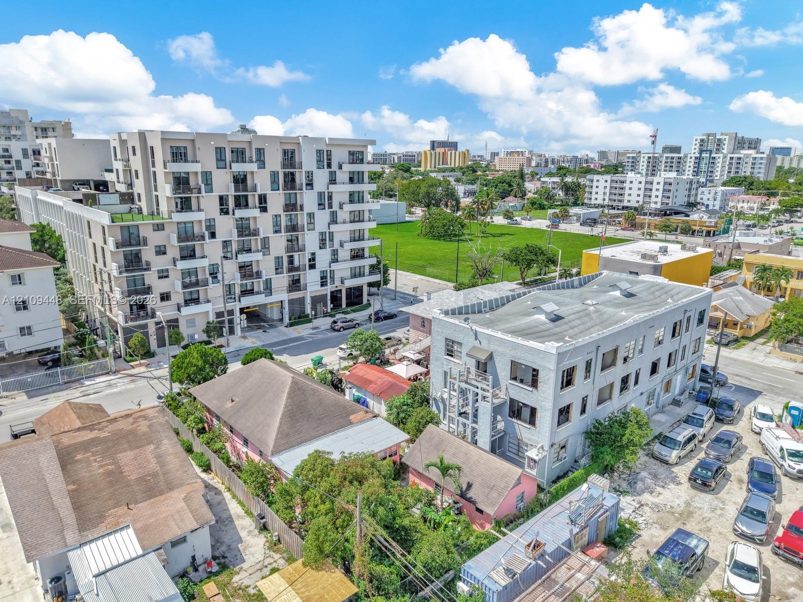 Aerial perspective of a multi-story urban residential building featuring a light-toned exterior facade, grid-pattern fenestration, and private balconies