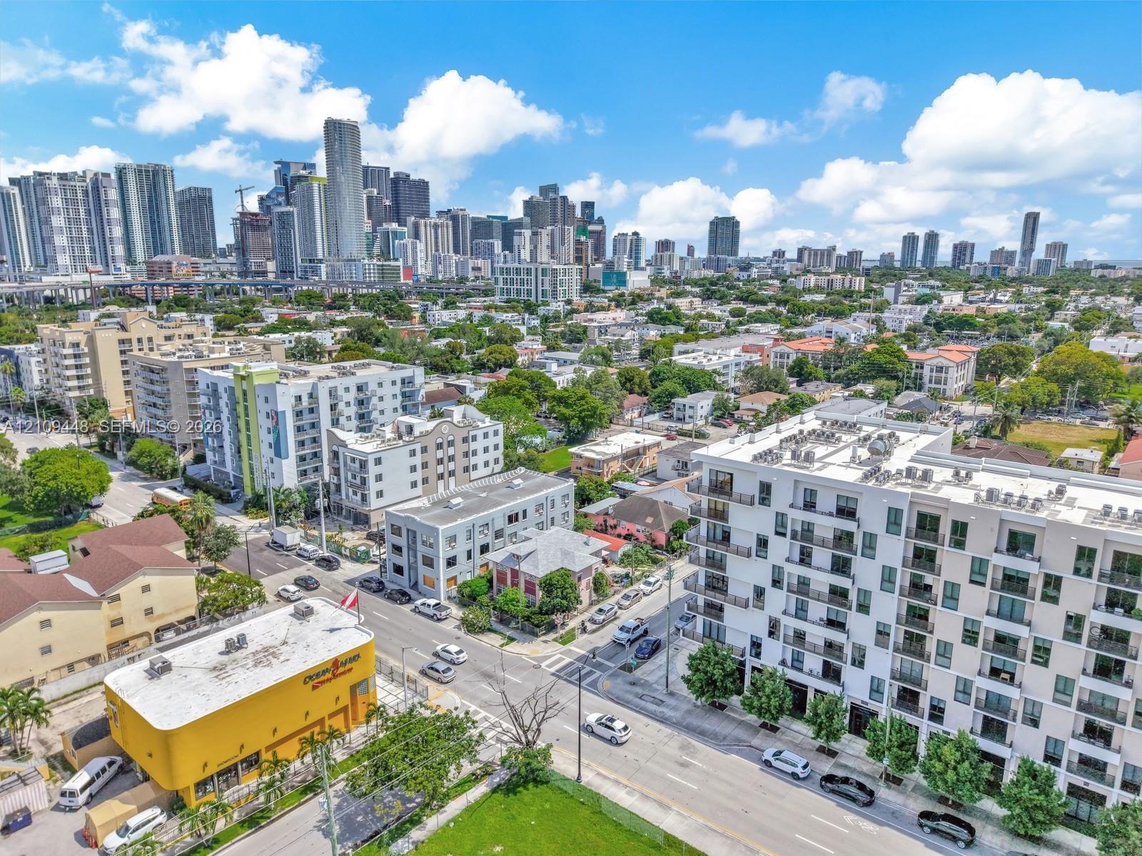 Aerial perspective of a multi-story residential building featuring private balconies, floor-to-ceiling windows, and a flat-roof design, set against a metropolitan skyline