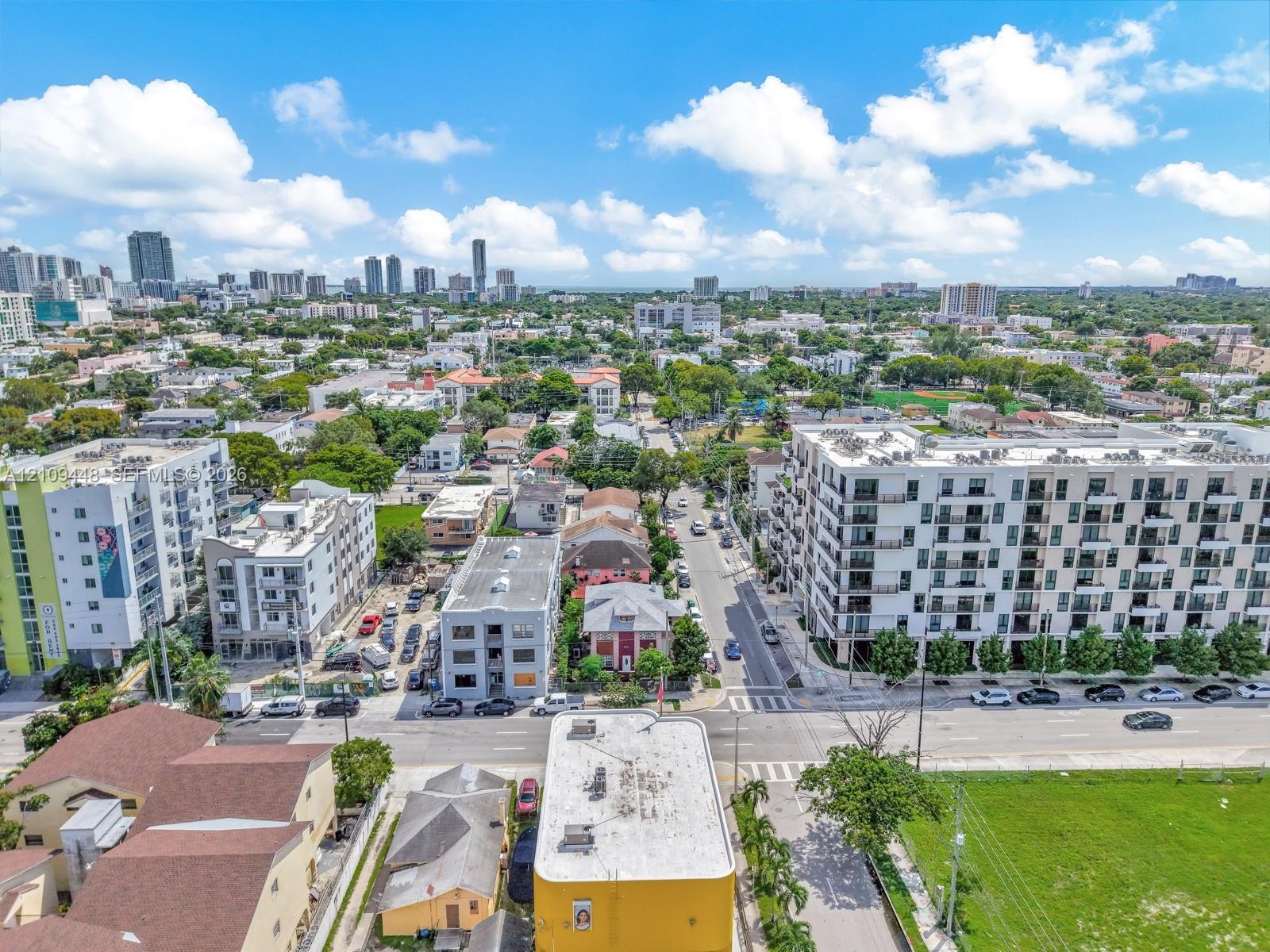 Aerial perspective of the urban landscape featuring multi-story residential architecture, paved roadways, and a metropolitan skyline backdrop
