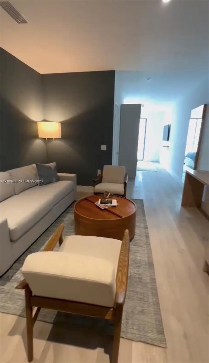 Interior space featuring light wood-finish flooring, a charcoal-toned accent wall, and a recessed ceiling lighting fixture Interior space featuring light wood-finish flooring, a charcoal-toned accent wall, and a recessed ceiling lighting fixture