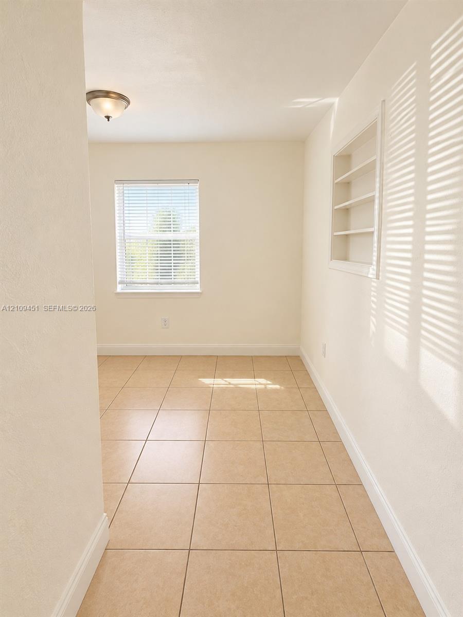 Room featuring neutral tile flooring, recessed wall shelving, and a semi-flush mount light fixture