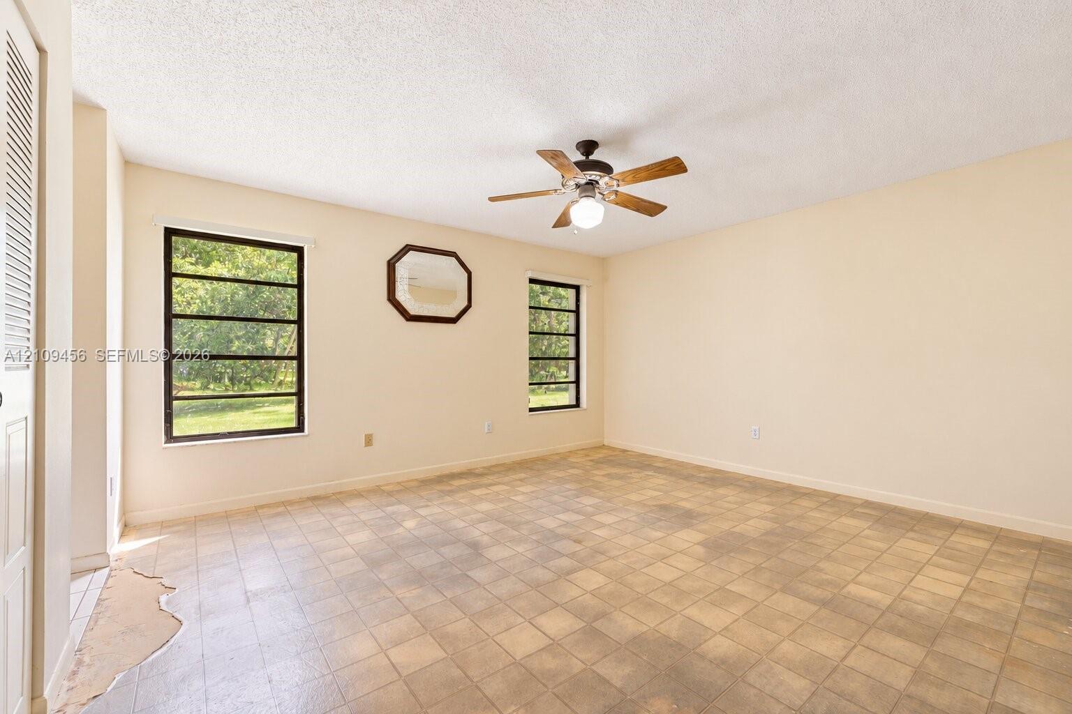 Room interior featuring ceramic tile flooring, a multi-blade ceiling fan with integrated lighting, and dual windows
