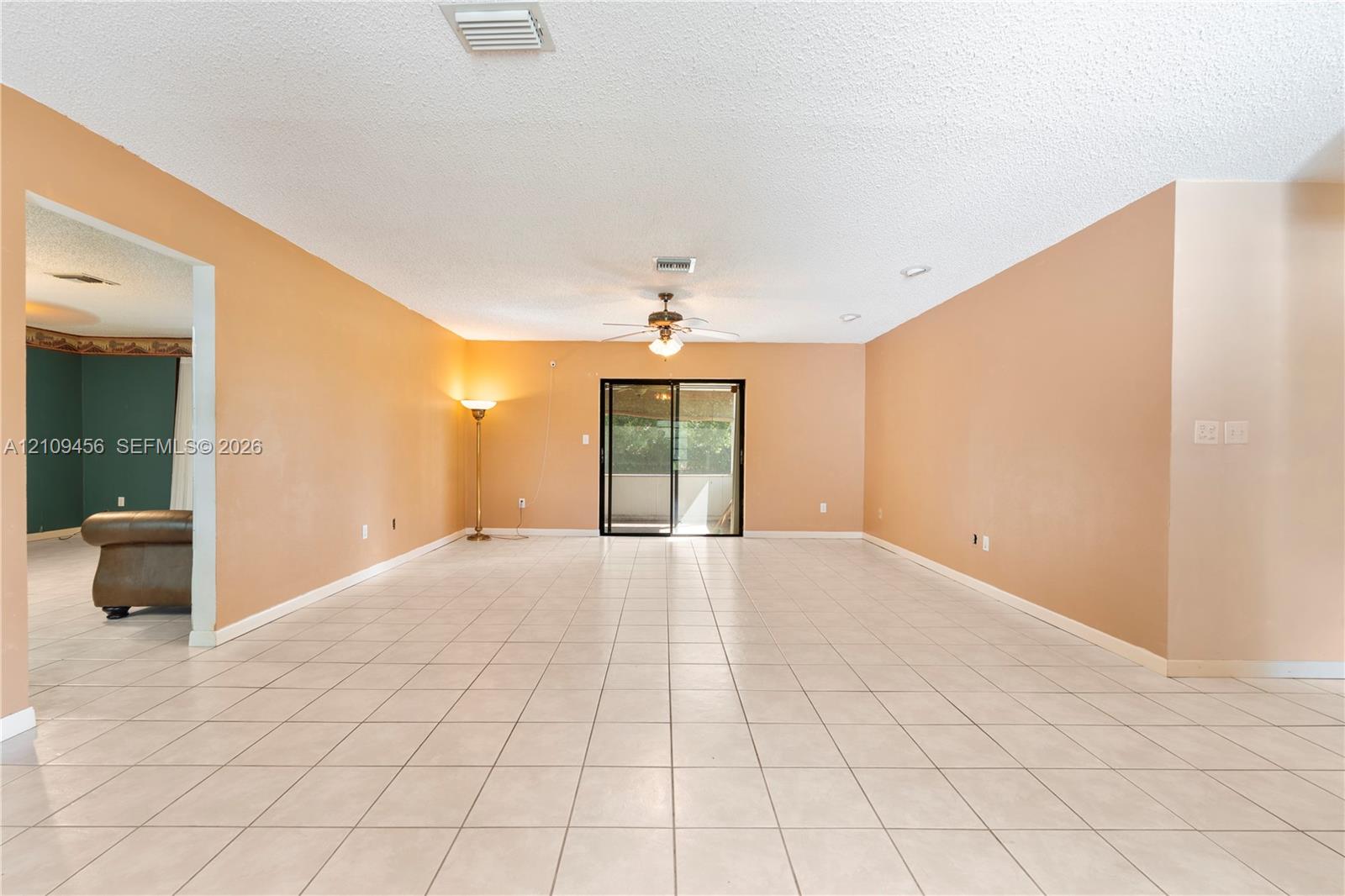 Neutral-toned ceramic tile flooring, ceiling fan with integrated lighting, and sliding glass patio door