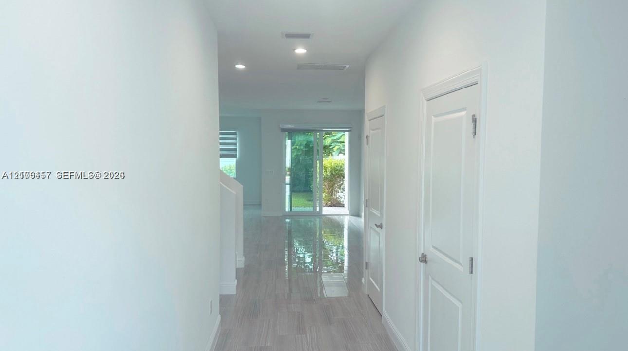 Interior hallway featuring light-toned wood-finish flooring, recessed lighting, and sliding glass doors